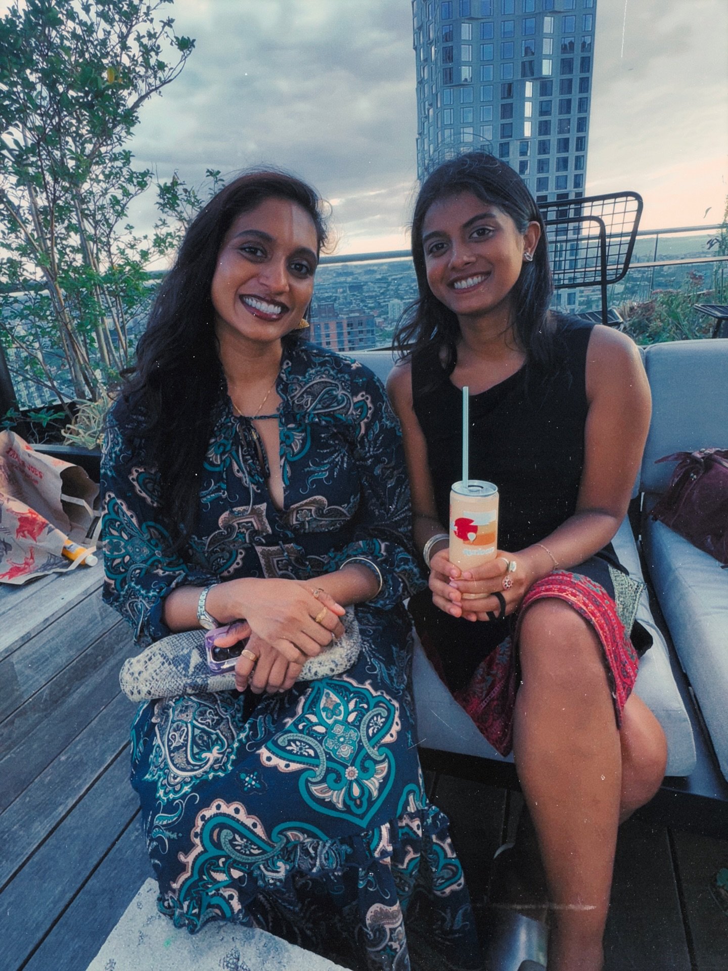 Two friends together on a rooftop with the city skyline behind them