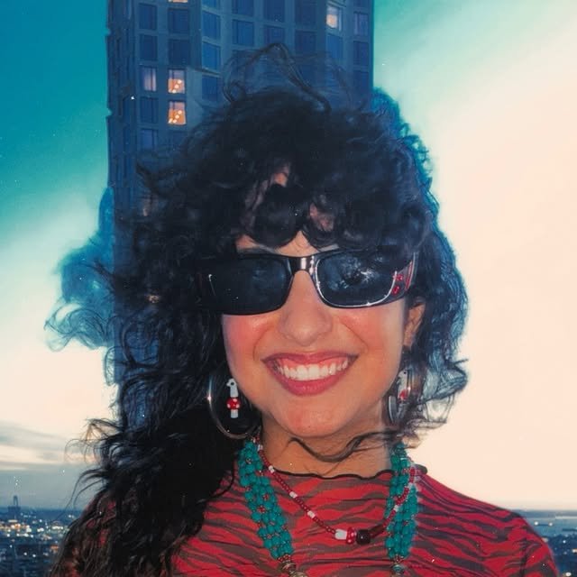 A calm, smiling adult on a New York rooftop